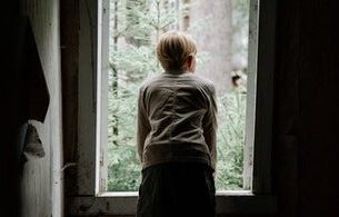 Μοναχική φιγούρα κοιτάει από ένα παράθυρο