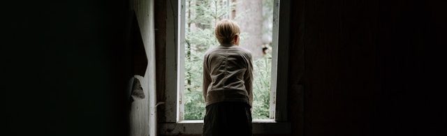 Μοναχική φιγούρα κοιτάει από ένα παράθυρο