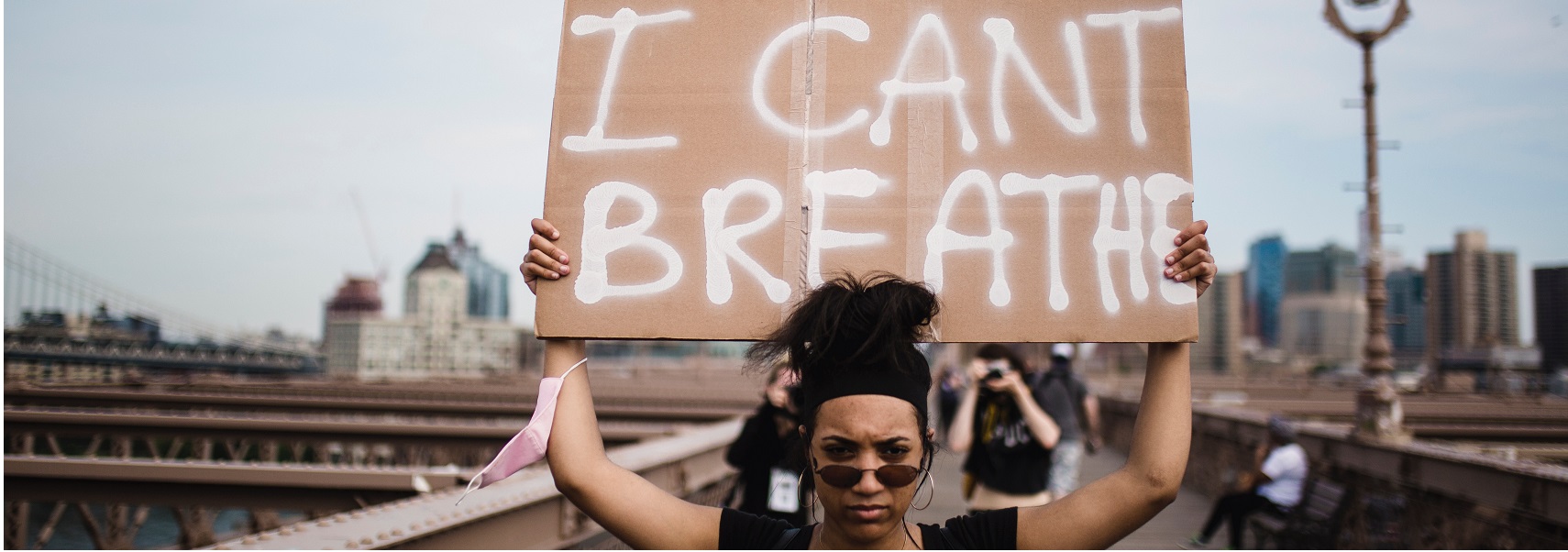 Μία γυναίκα διαδηλώνει κρατώντας ένα χαρτόνι το οποίο γράφει "I Can't Breathe"